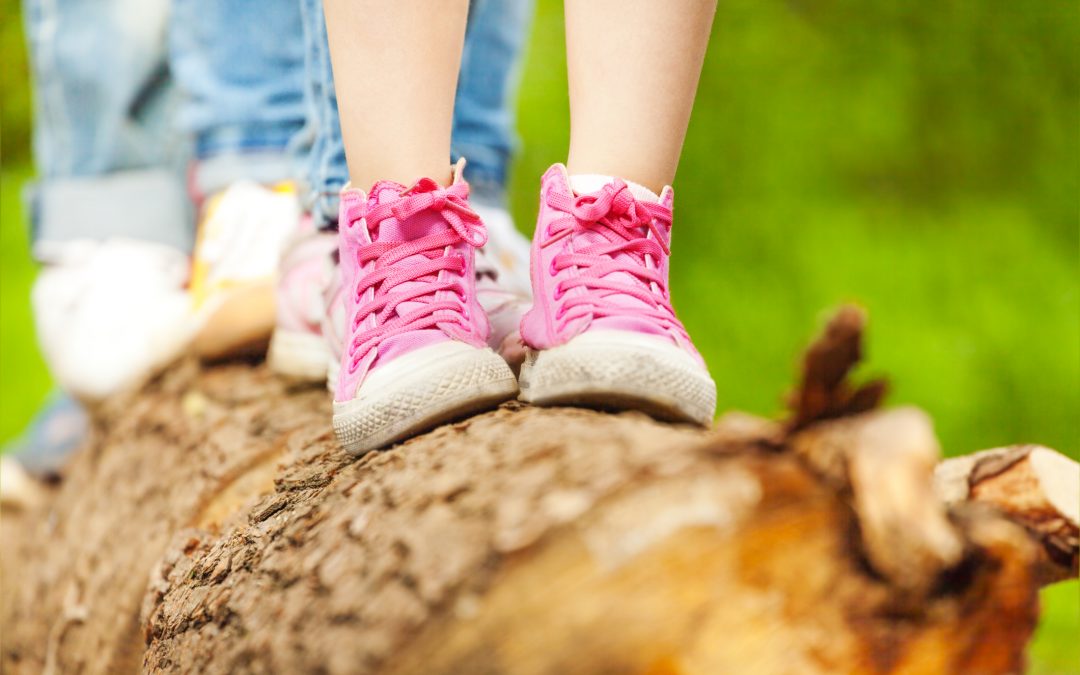 Children's feet in pink sneakers standing on a log