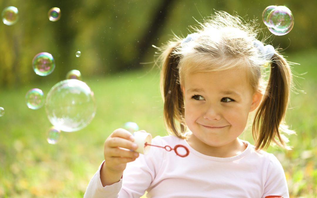 Cute little girl is blowing a soap bubbles